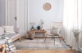 dywan-vintage-marylou-kremowy-aranzacja--w-salonie-na-jasnej-podlodze-z-jasnymi-scianami-sofa-i-stolikiem-pod-sciana-na-srodku-krzeslo.webp