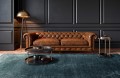 dywan-vintage-marylou-ciemny-szary-aranzacja--w-salonie-na-jasnej-podlodze-z-ciemnymi-scianami-skorzana-sofa-dwoma-stolikami-lamp.webp