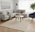 dywan-nowoczesny-art-3d-geometria-kremowy-aranzacja-w-salonie-z-jasna-sofa-duzym-oknem-w-tle-i-niebieskim-fotelem-na-srodku-dywanu-stolik-kawowy.jpg